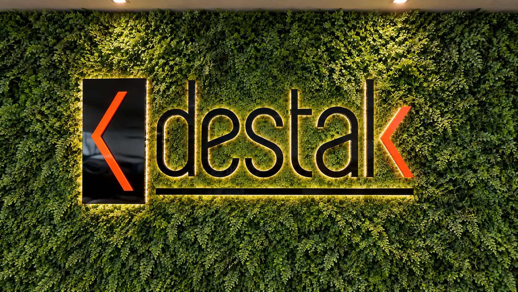 Parede verde com a marca Destak iluminada